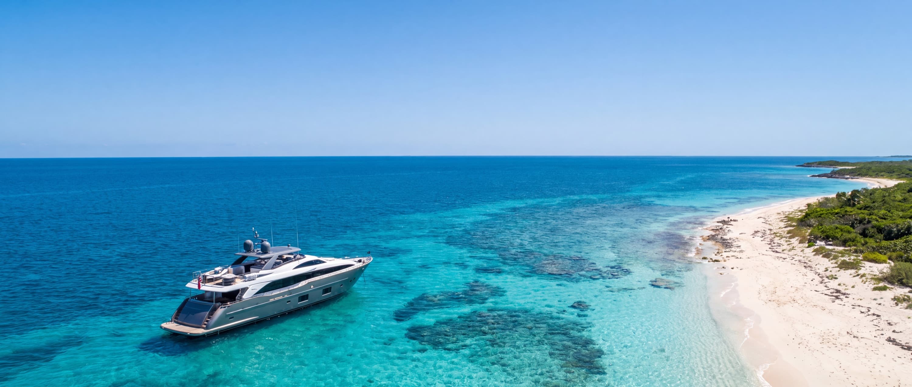 A motor yacht anchored beside a sunlit beach